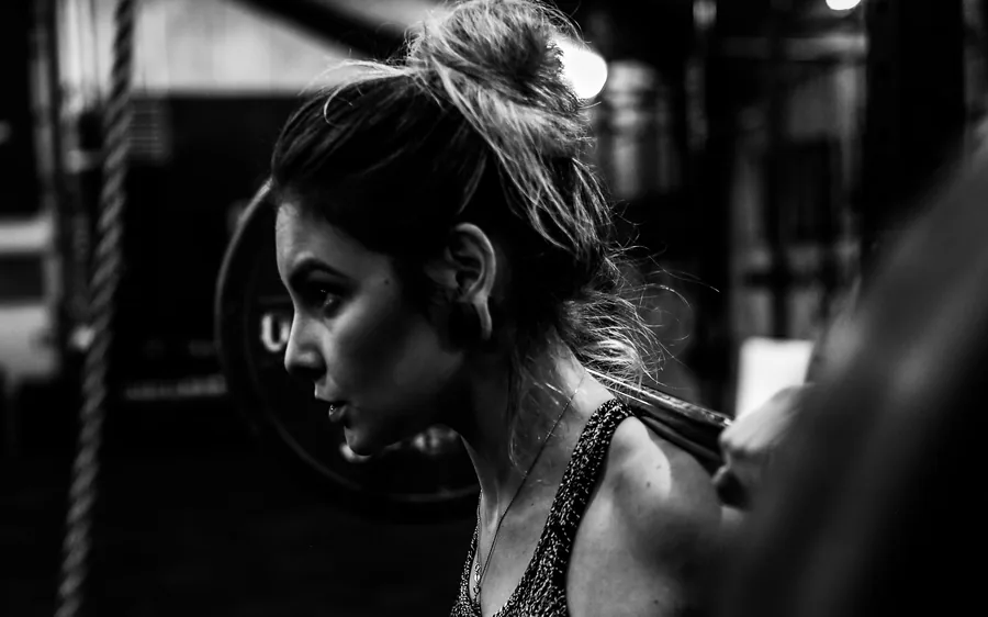 An athlete steadying a loaded barbell across her shoulders before a lift.