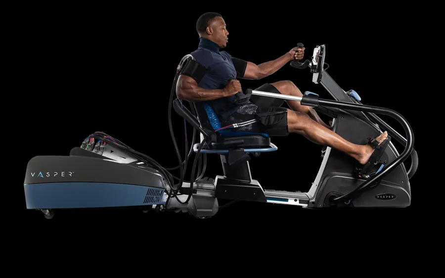 A person training on a seated Vasper machine with cooling and compression cuffs fitted.